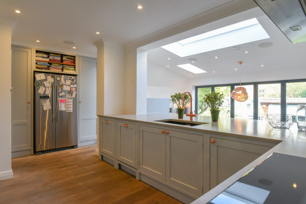 Photo of a mid-sized contemporary u-shaped eat-in kitchen in London with an undermount sink, beaded inset cabinets, grey cabinets, stainless steel appliances, no island and grey benchtop.