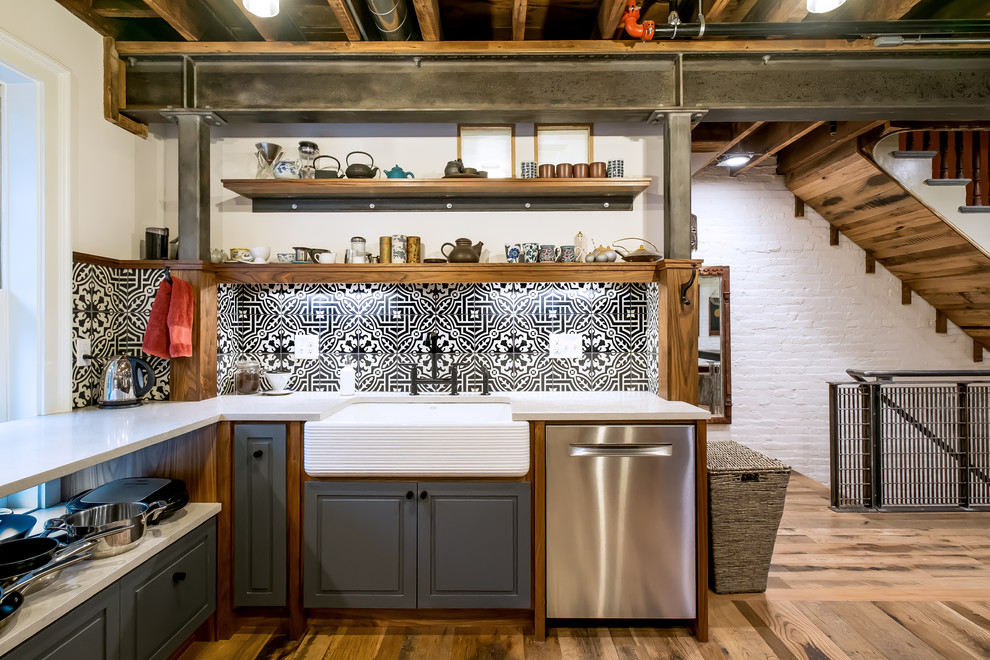 Mid-sized eclectic u-shaped separate kitchen in Boston with raised-panel cabinets, grey cabinets, light hardwood floors, white benchtop, a farmhouse sink, solid surface benchtops, multi-coloured splashback, cement tile splashback, stainless steel appliances, no island and brown floor.