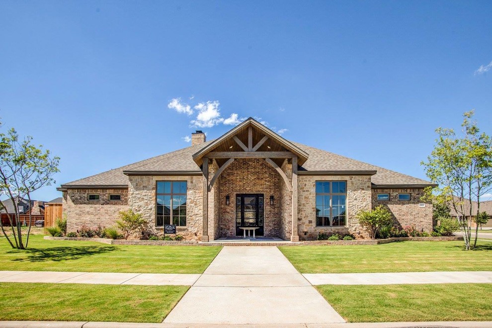Large country one-storey brick brown house exterior in Austin with a hip roof and a shingle roof.