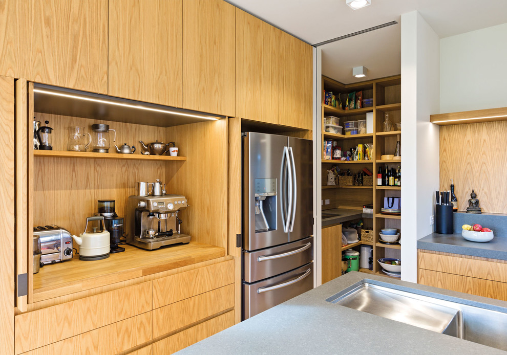 Photo of a mid-sized contemporary galley open plan kitchen in Melbourne with an undermount sink, flat-panel cabinets, medium wood cabinets, solid surface benchtops, grey splashback, stone slab splashback, stainless steel appliances, light hardwood floors, with island, brown floor and grey benchtop.