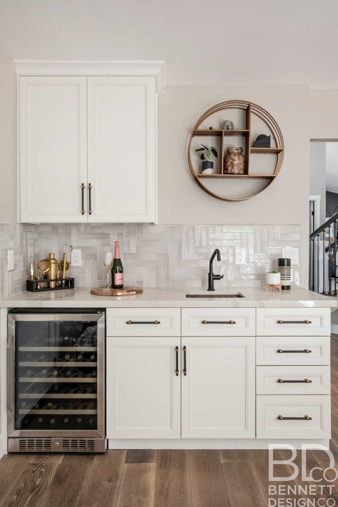 Inspiration for a mid-sized country single-wall wet bar in San Francisco with an undermount sink, recessed-panel cabinets, white cabinets, quartz benchtops, beige splashback, porcelain splashback, light hardwood floors, beige floor and white benchtop.