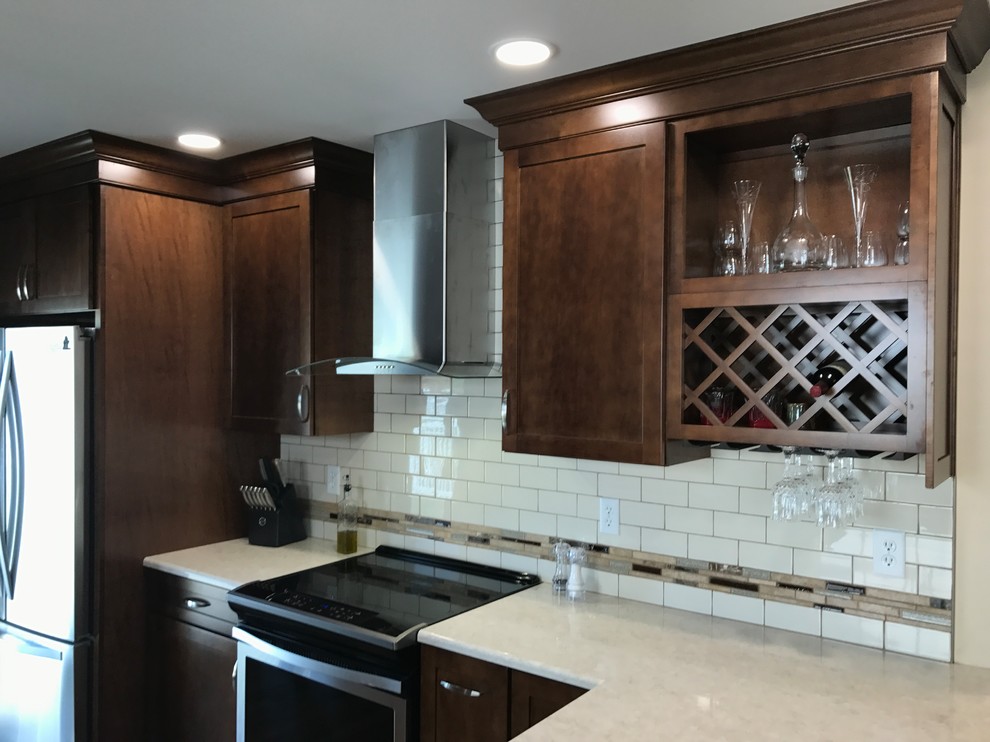 Mid-sized traditional galley eat-in kitchen in Other with an undermount sink, shaker cabinets, medium wood cabinets, quartz benchtops, beige splashback, stainless steel appliances, medium hardwood floors, a peninsula and brown floor.