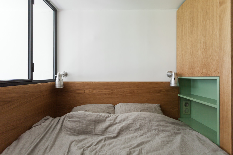Photo of a small scandinavian loft-style bedroom in Paris with painted wood floors and wood walls.