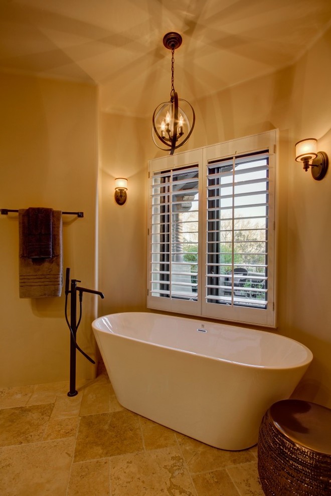 This is an example of an expansive master bathroom in Phoenix with raised-panel cabinets, dark wood cabinets, a freestanding tub, an alcove shower, beige tile, stone tile, beige walls, travertine floors, an undermount sink and granite benchtops.