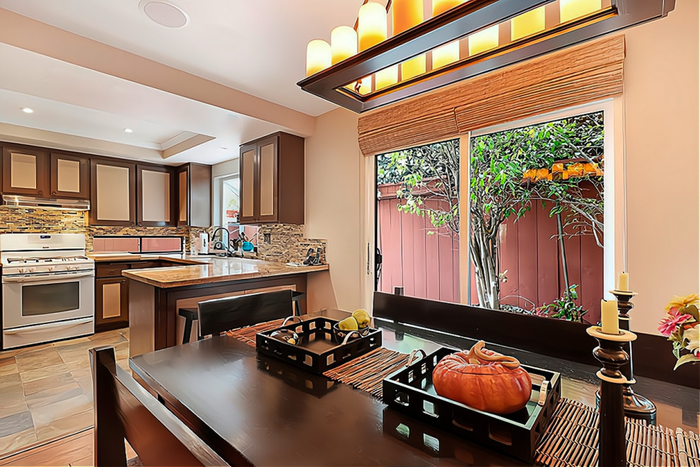 This is an example of a small asian u-shaped eat-in kitchen in Los Angeles with an undermount sink, recessed-panel cabinets, granite benchtops, multi-coloured splashback, glass tile splashback, white appliances, slate floors, a peninsula, multi-coloured floor, yellow benchtop and recessed.