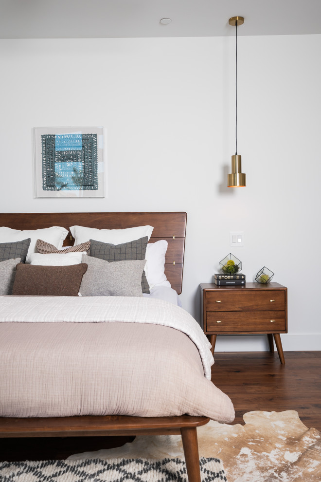 Contemporary bedroom in Los Angeles with white walls, dark hardwood floors and brown floor.