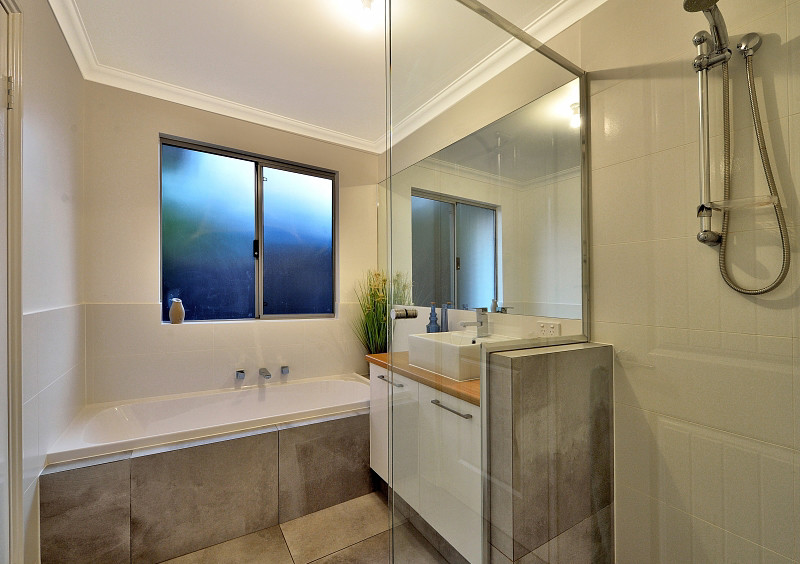 Inspiration for a small contemporary bathroom in Perth with white cabinets, white tile, white walls, grey floor, flat-panel cabinets, an alcove tub, a corner shower, ceramic tile, a vessel sink, wood benchtops and a hinged shower door.
