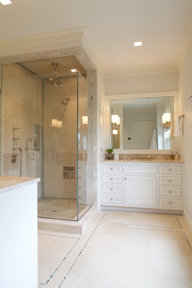 Photo of a large transitional master bathroom in New York with an undermount sink, recessed-panel cabinets, white cabinets, limestone benchtops, a double shower, multi-coloured tile, stone tile and limestone floors.