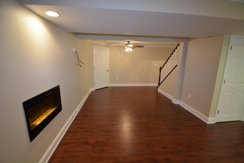 Design ideas for a large traditional walk-out basement in Baltimore with beige walls, dark hardwood floors and a ribbon fireplace.