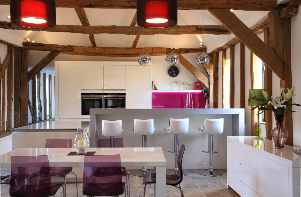Mid-sized contemporary galley eat-in kitchen in Hertfordshire with flat-panel cabinets, white cabinets, pink splashback and glass sheet splashback.