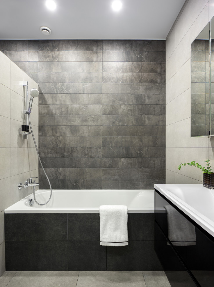 This is an example of a mid-sized contemporary master wet room bathroom in Moscow with flat-panel cabinets, black cabinets, an undermount tub, a wall-mount toilet, black tile, ceramic tile, grey walls, ceramic floors, a drop-in sink, grey floor and a hinged shower door.