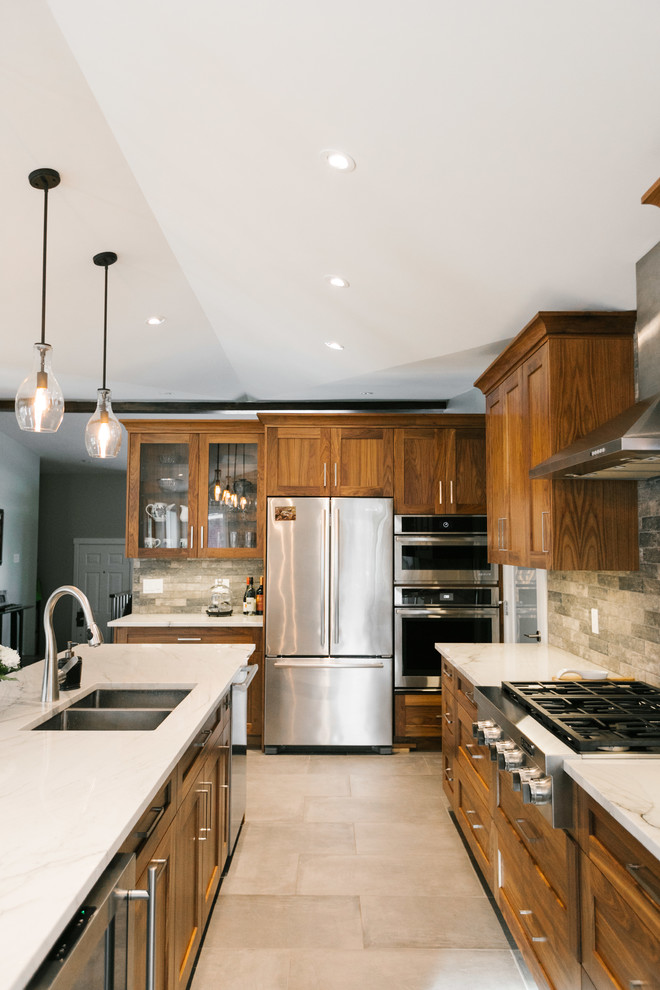 Mid-sized modern galley kitchen in Calgary with an undermount sink, shaker cabinets, medium wood cabinets, granite benchtops, grey splashback, stone tile splashback, stainless steel appliances, porcelain floors, with island, grey floor and white benchtop.