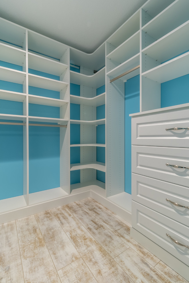Photo of a mid-sized traditional gender-neutral walk-in wardrobe in Minneapolis with raised-panel cabinets, white cabinets and vinyl floors.