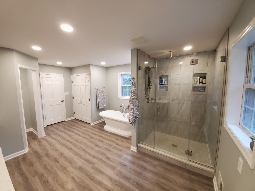 Large minimalist master laminate floor, brown floor and double-sink bathroom photo in Philadelphia with a hot tub, a two-piece toilet, blue walls, an undermount sink, granite countertops, a hinged shower door, white countertops, a niche and a freestanding vanity