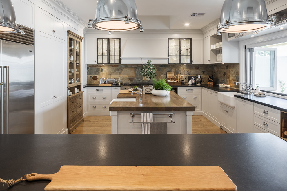 This is an example of a large country kitchen in Perth with shaker cabinets, grey cabinets, granite benchtops, brown splashback, stainless steel appliances, medium hardwood floors, a farmhouse sink, black benchtop, slate splashback and multiple islands.