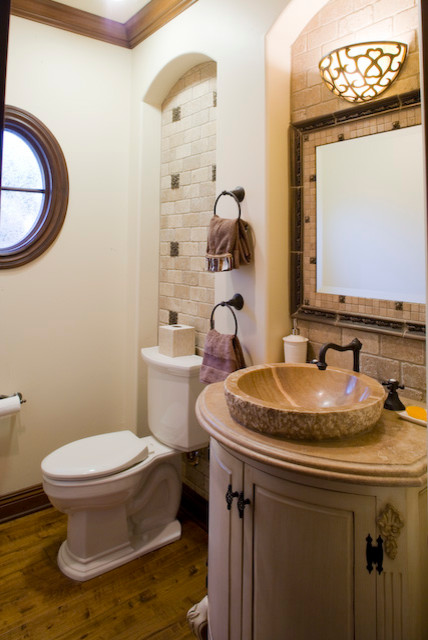 Mid-sized mediterranean powder room in Orange County with furniture-like cabinets, beige cabinets, a two-piece toilet, beige tile, beige walls, medium hardwood floors, a vessel sink, stone tile and granite benchtops.