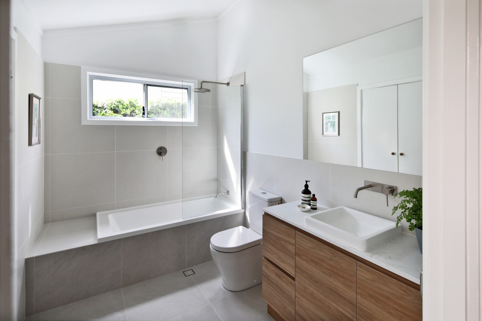 This is an example of a mid-sized contemporary master bathroom in Perth with light wood cabinets, a drop-in tub, a shower/bathtub combo, gray tile, porcelain tile, porcelain floors, a drop-in sink, grey floor and a hinged shower door.