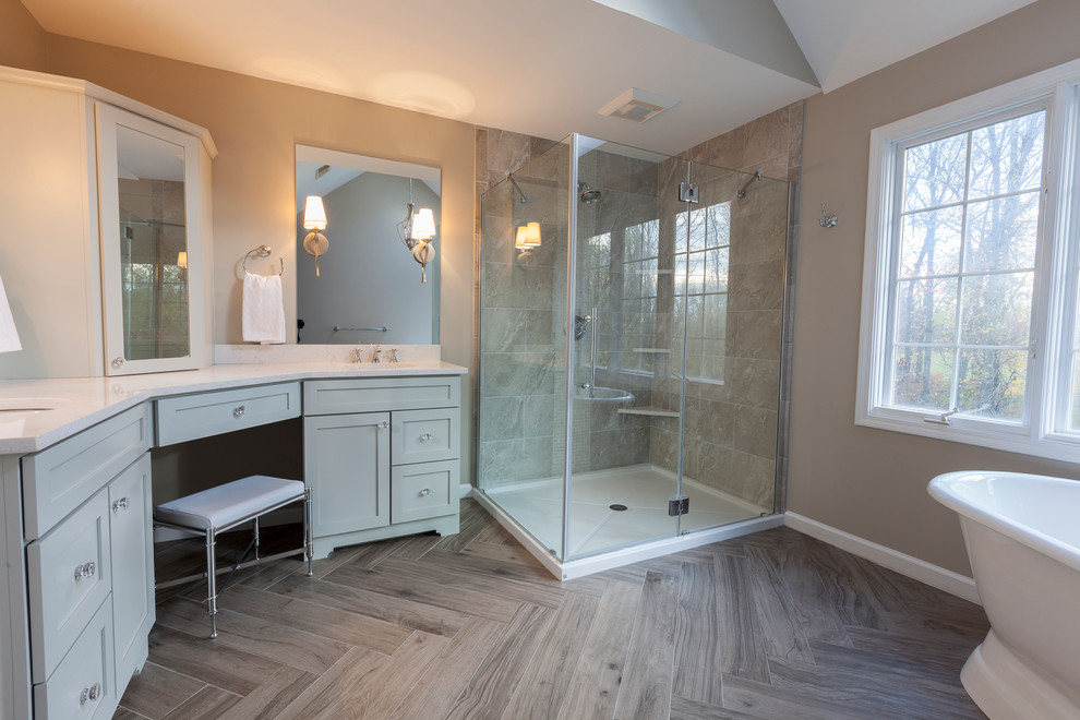 Inspiration for a mid-sized transitional master gray tile and porcelain tile porcelain tile and gray floor freestanding bathtub remodel in New York with flat-panel cabinets, gray cabinets, a two-piece toilet, gray walls, an undermount sink, quartz countertops and a hinged shower door