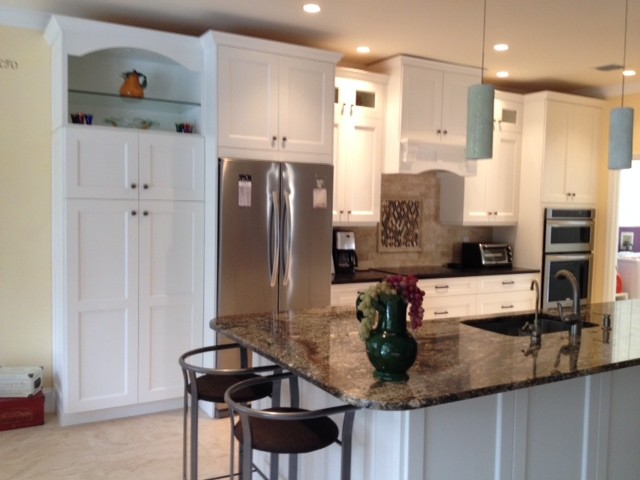 Mid-sized transitional travertine floor open concept kitchen photo with an undermount sink, shaker cabinets, white cabinets, granite countertops, beige backsplash, stone tile backsplash, stainless steel appliances and an island
