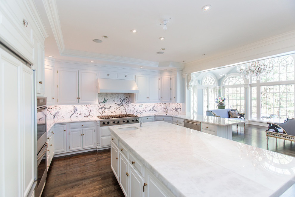 Photo of an expansive traditional u-shaped open plan kitchen in Boston with a drop-in sink, recessed-panel cabinets, white cabinets, marble benchtops, multi-coloured splashback, ceramic splashback, stainless steel appliances, dark hardwood floors, with island, brown floor and white benchtop.