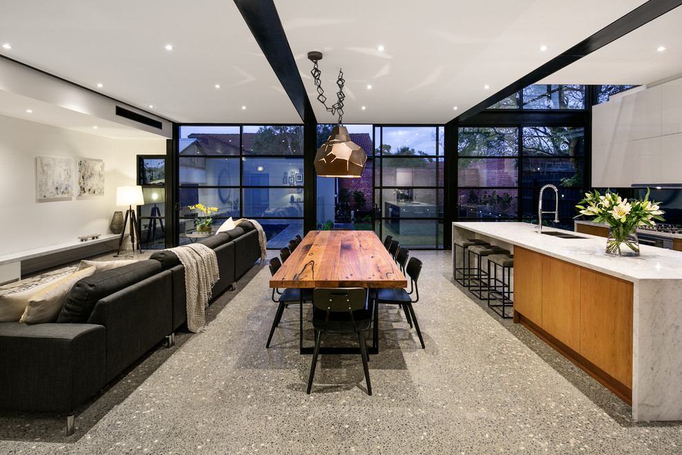 Large open plan dining in Melbourne with white walls and concrete floors.
