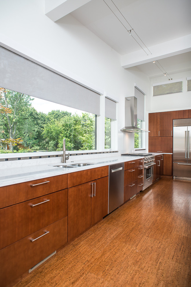 Photo of a large asian l-shaped eat-in kitchen in Detroit with a double-bowl sink, flat-panel cabinets, medium wood cabinets, quartzite benchtops, white splashback, stone slab splashback, stainless steel appliances, cork floors and with island.