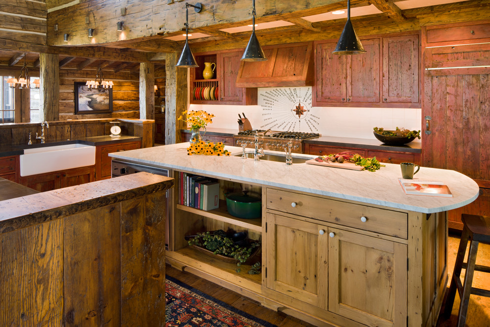Example of a mountain style l-shaped medium tone wood floor kitchen design with shaker cabinets, medium tone wood cabinets, marble countertops, a farmhouse sink, paneled appliances, beige walls and an island
