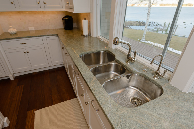 Kitchen - transitional medium tone wood floor kitchen idea in Boston with a triple-bowl sink, recessed-panel cabinets, white cabinets, granite countertops, white backsplash, mosaic tile backsplash, stainless steel appliances and an island