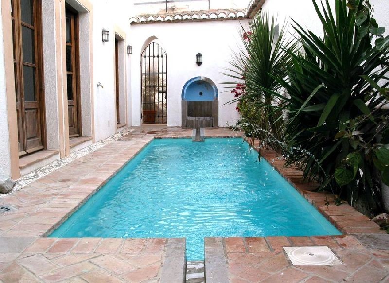 Photo of a small courtyard rectangular lap pool in Other with a water feature and tile.