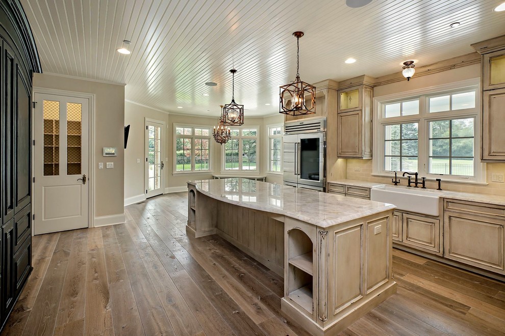 Design ideas for a mid-sized country l-shaped eat-in kitchen in Chicago with a farmhouse sink, raised-panel cabinets, distressed cabinets, marble benchtops, beige splashback, ceramic splashback, stainless steel appliances, medium hardwood floors and with island.