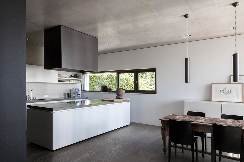 Large contemporary galley eat-in kitchen in Stuttgart with a drop-in sink, flat-panel cabinets, white cabinets, grey splashback, concrete floors, with island and grey floor.