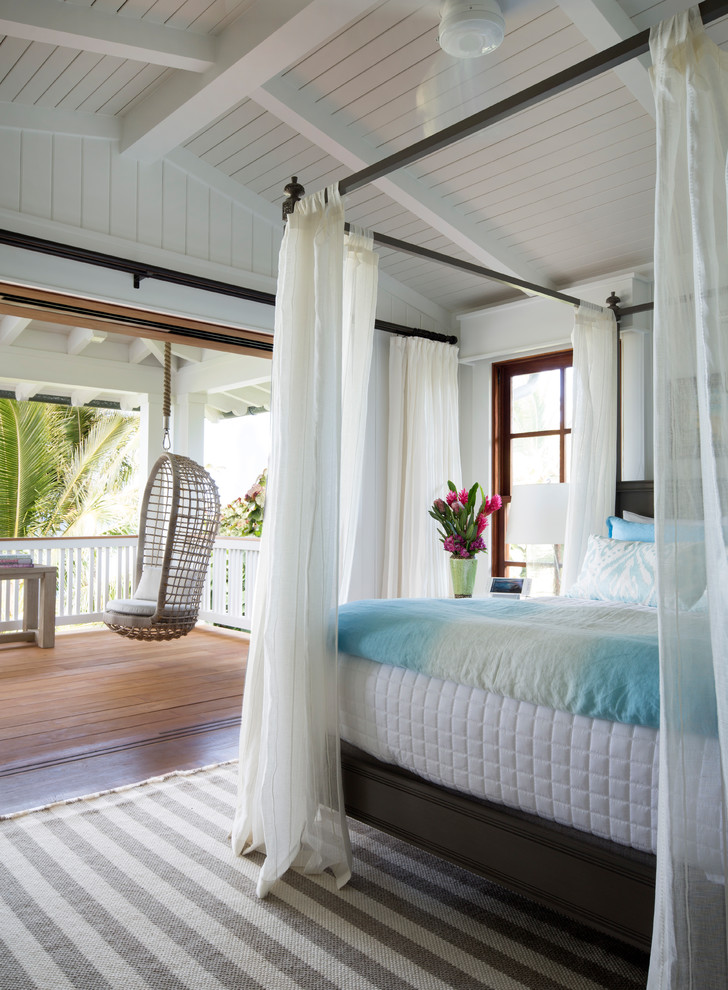 Photo of a tropical master bedroom in Hawaii with white walls, medium hardwood floors, no fireplace and brown floor.