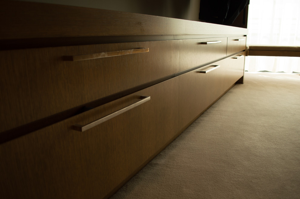This is an example of an expansive modern gender-neutral walk-in wardrobe in Portland with flat-panel cabinets, medium wood cabinets and carpet.