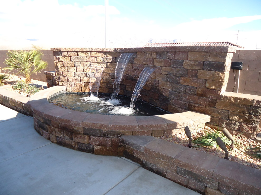 This is an example of a large contemporary backyard full sun xeriscape for summer in Las Vegas with a water feature and brick pavers.