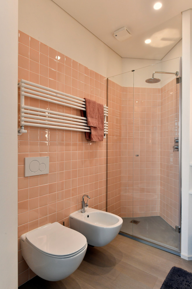 Bild på ett litet funkis svart svart badrum med dusch, med luckor med profilerade fronter, vita skåp, en hörndusch, en vägghängd toalettstol, rosa kakel, keramikplattor, vita väggar, ljust trägolv, ett fristående handfat, bänkskiva i kvarts, grått golv och dusch med gångjärnsdörr