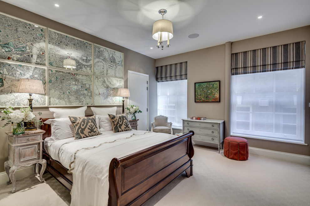 This is an example of a transitional master bedroom in London with beige walls and carpet.