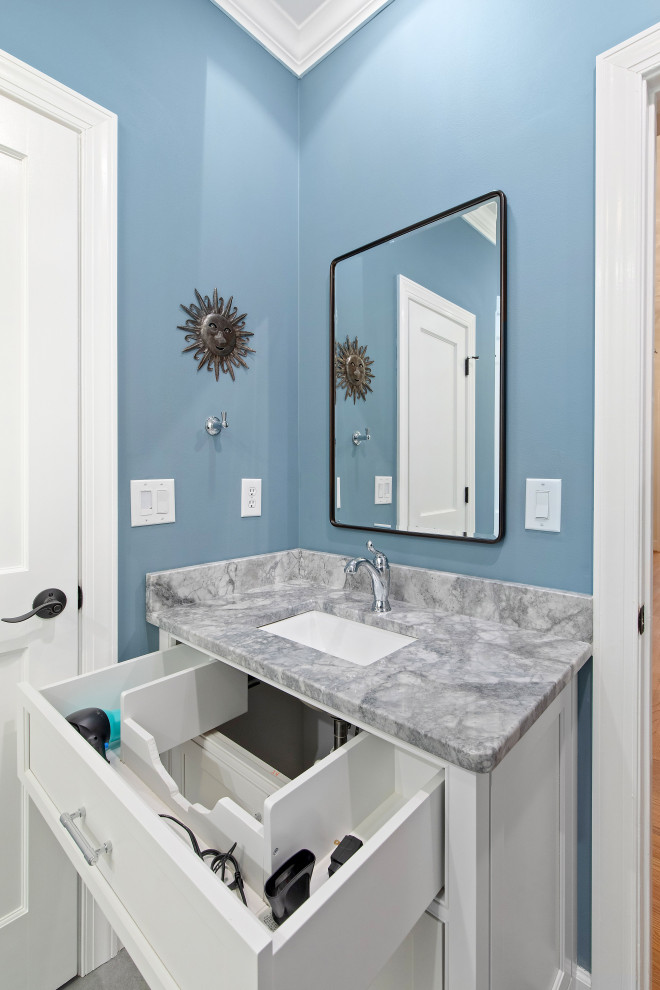 Modelo de cuarto de baño único clásico renovado con armarios con rebordes decorativos, puertas de armario blancas, combinación de ducha y bañera, paredes azules, suelo de baldosas de porcelana, lavabo bajoencimera, encimera de granito, suelo gris, encimeras multicolor y hornacina