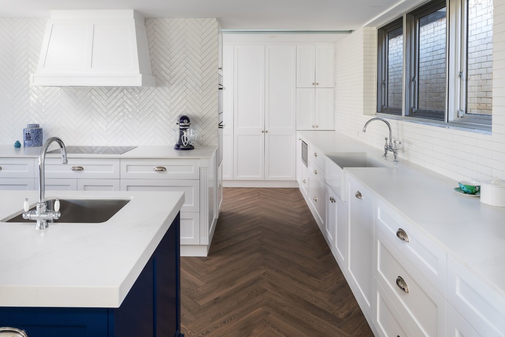 Inspiration for a transitional galley kitchen in Hobart with a farmhouse sink, shaker cabinets, white cabinets, marble benchtops, white splashback, stainless steel appliances, medium hardwood floors, with island, beige floor and white benchtop.