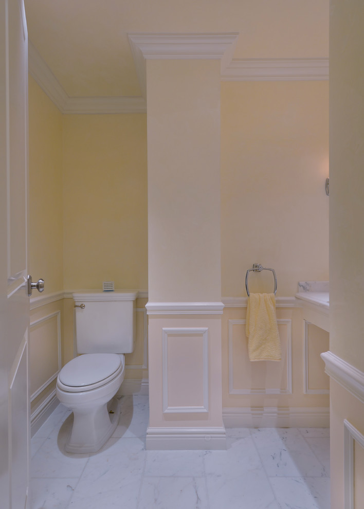 Small transitional bathroom in New York with a vessel sink, marble benchtops, a one-piece toilet, yellow walls and marble floors.