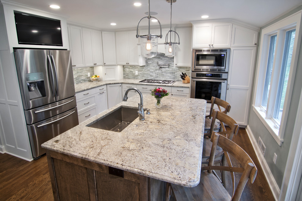 Mid-sized transitional l-shaped kitchen in Minneapolis with an undermount sink, shaker cabinets, white cabinets, granite benchtops, grey splashback, matchstick tile splashback, stainless steel appliances, medium hardwood floors, with island and brown floor.
