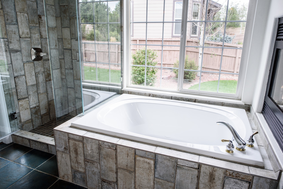 Example of a large transitional master gray tile and glass tile concrete floor drop-in bathtub design in Denver with white walls