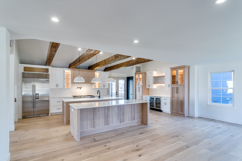 Kitchen - large transitional exposed beam kitchen idea in Cincinnati with flat-panel cabinets, white cabinets, marble countertops, white backsplash, subway tile backsplash, stainless steel appliances, two islands and white countertops