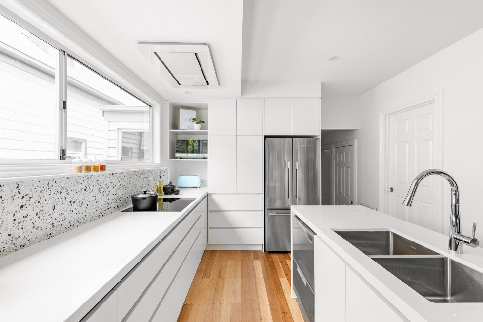 Immagine di una cucina minimalista di medie dimensioni con lavello a doppia vasca, ante bianche, paraspruzzi bianco, elettrodomestici in acciaio inossidabile, 2 o più isole, top giallo e soffitto a volta