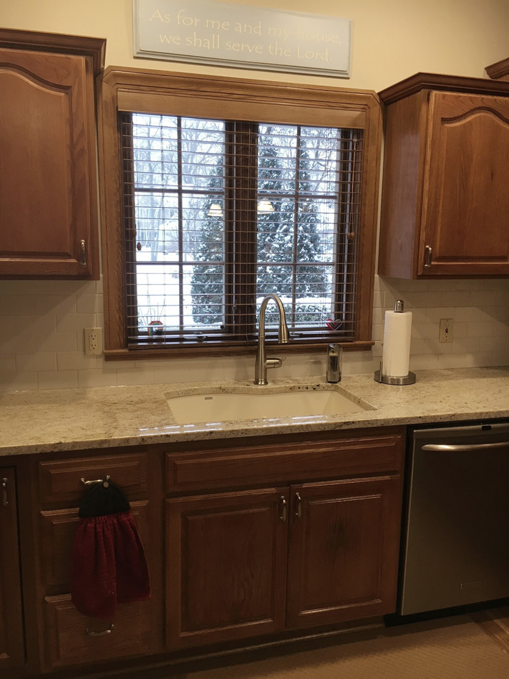 Eat-in kitchen - large transitional u-shaped medium tone wood floor eat-in kitchen idea with an undermount sink, raised-panel cabinets, medium tone wood cabinets, granite countertops, white backsplash, ceramic backsplash, stainless steel appliances and an island