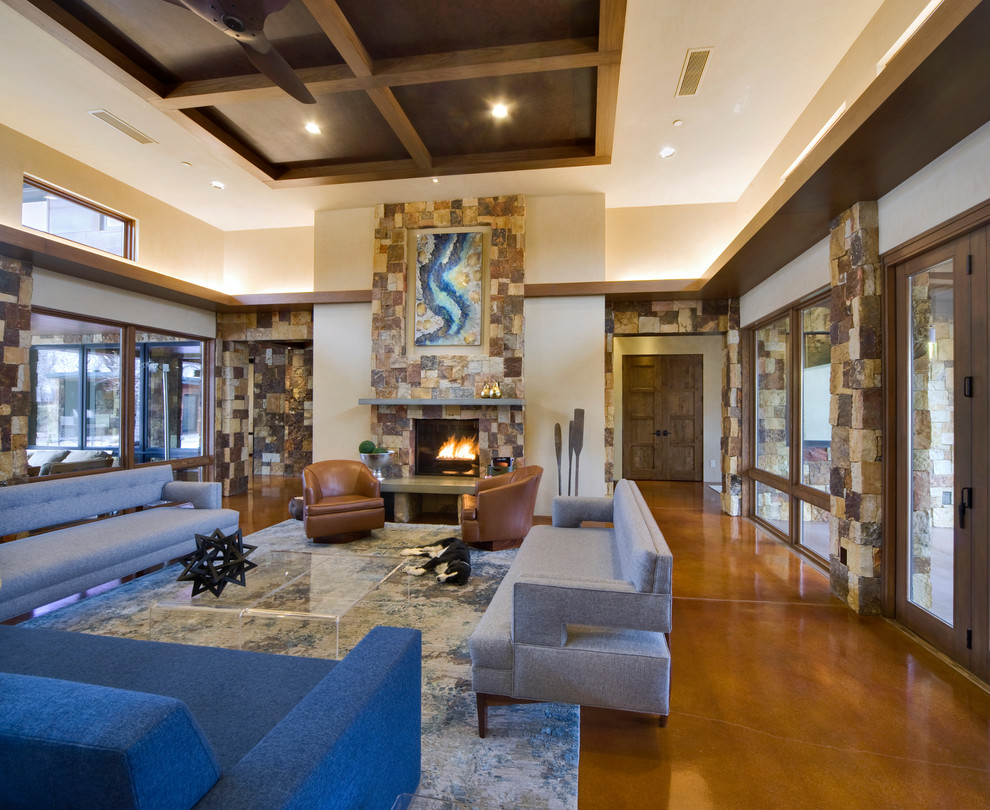 This is an example of a large contemporary open concept living room in Albuquerque with beige walls, concrete floors, a standard fireplace and a stone fireplace surround.