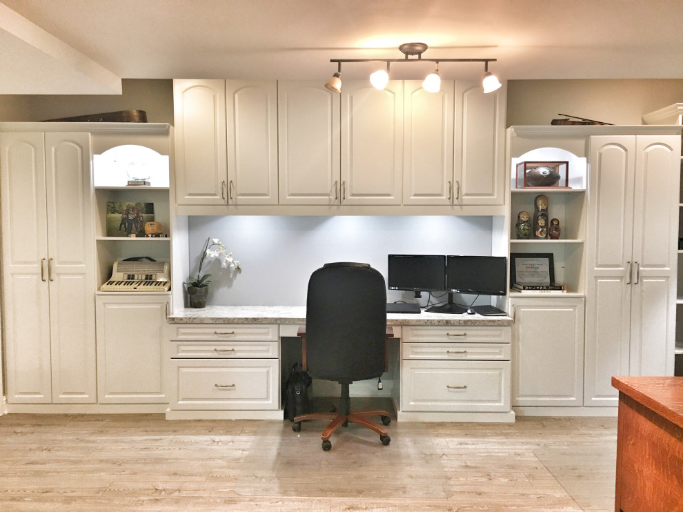 Large transitional home office in St Louis with laminate floors and a built-in desk.
