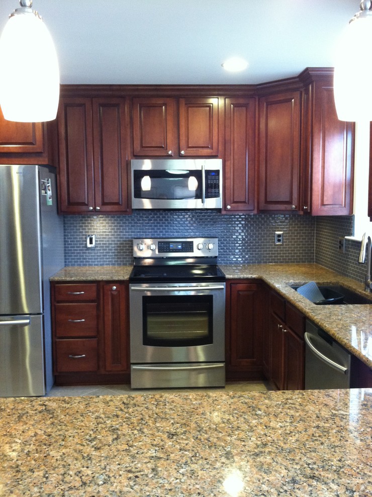 Inspiration for a large transitional u-shaped ceramic tile and beige floor enclosed kitchen remodel with an undermount sink, raised-panel cabinets, dark wood cabinets, granite countertops, blue backsplash, ceramic backsplash, stainless steel appliances and a peninsula