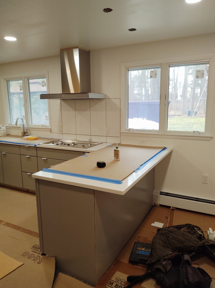 Mid-sized enclosed kitchen photo with flat-panel cabinets, gray cabinets and a peninsula