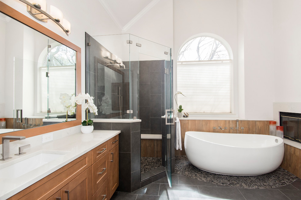Example of a mid-sized classic master gray tile and porcelain tile porcelain tile and gray floor freestanding bathtub design in Dallas with flat-panel cabinets, brown cabinets, a one-piece toilet, gray walls, an undermount sink, quartzite countertops, a hinged shower door and white countertops
