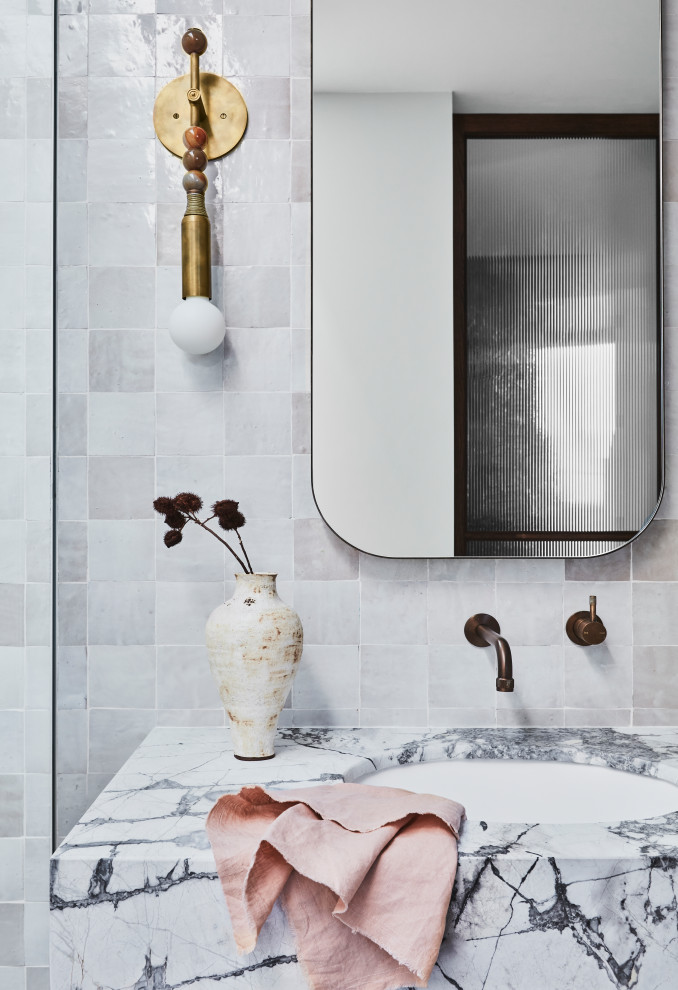 This is an example of a large contemporary master bathroom in Sydney with louvered cabinets, brown cabinets, a freestanding tub, an open shower, beige tile, porcelain tile, white walls, ceramic floors, an integrated sink, marble benchtops, multi-coloured floor, an open shower, grey benchtops, a double vanity and a floating vanity.